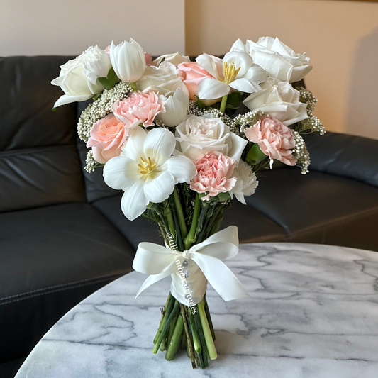 Bouquet of white Roses, white Tulips, and pink Carnations, Peach Roses, flowers with a decorative white bow . Graceful and classy bridal bouquet.