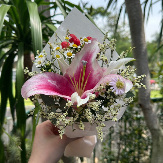 Bouquet of flowers held by a person with greenery in the background