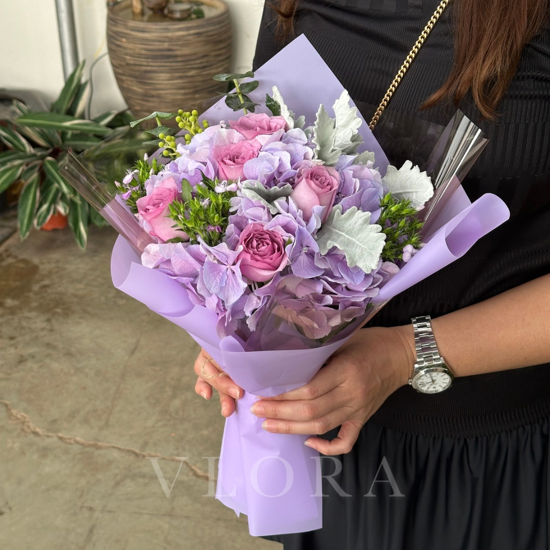 Bouquet of pink and purple hydrangeas flowers held by a person with a blurred background