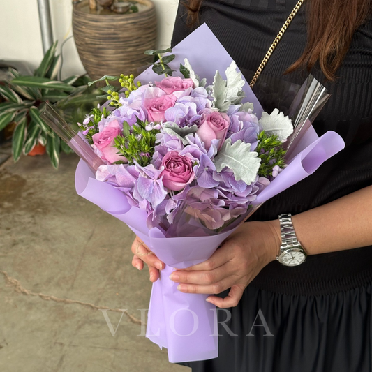 Bouquet of pink and purple hydrangeas flowers held by a person with a blurred background