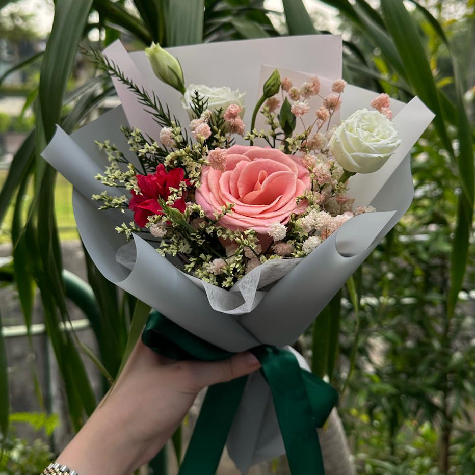 Bouquet of flowers held in front of a green leafy background