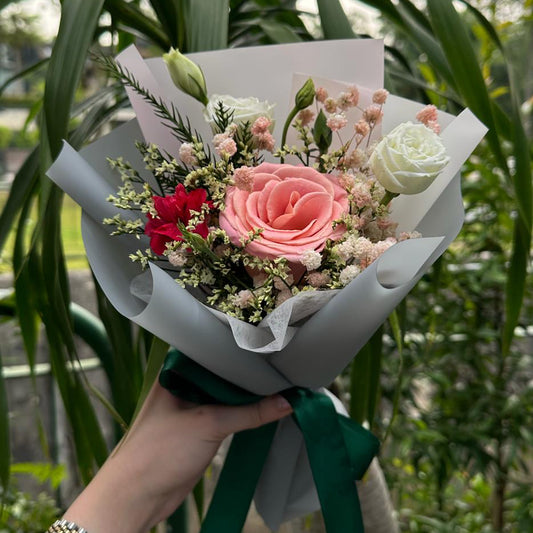 Bouquet of flowers held in front of a green leafy background
