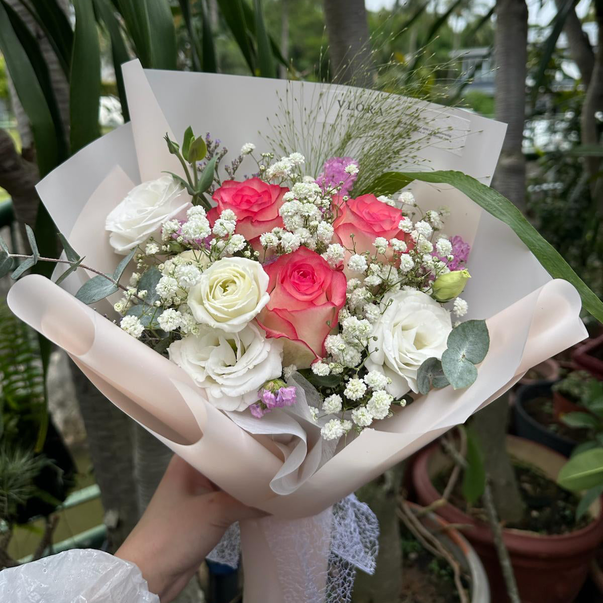 Bouquet of pink roses flowers held by a person with a blurred natural background