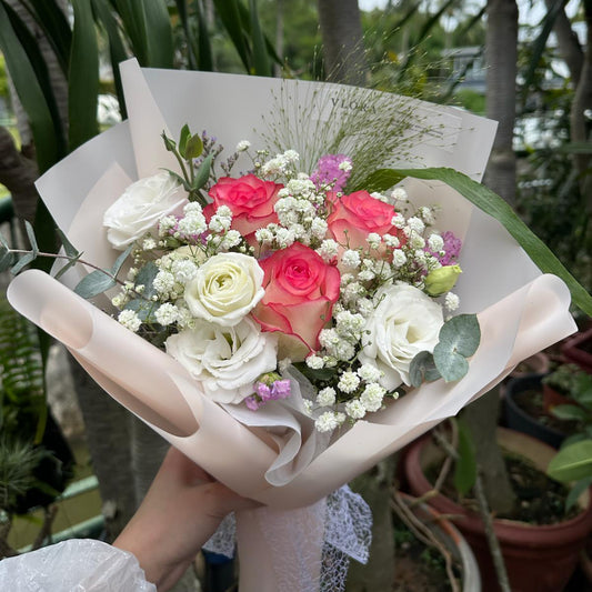 Bouquet of pink roses flowers held by a person with a blurred natural background