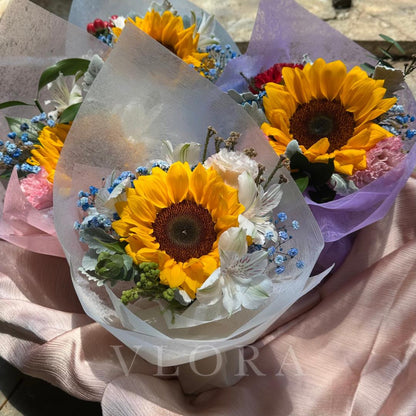 Bouquet of sunflowers and other flowers wrapped in paper with 'Viora' branding.