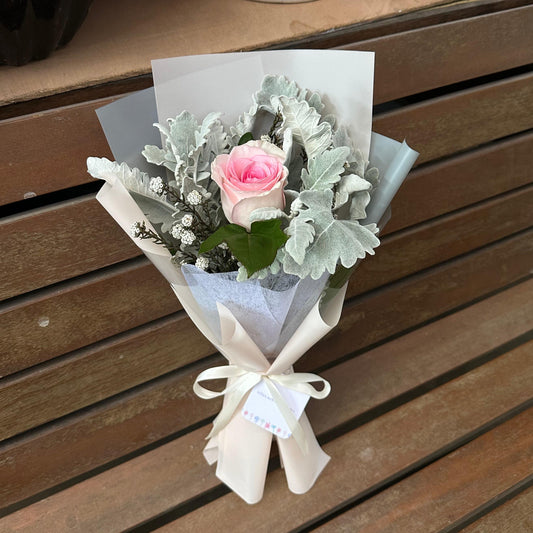 Bouquet of flowers wrapped in white paper on a wooden surface
