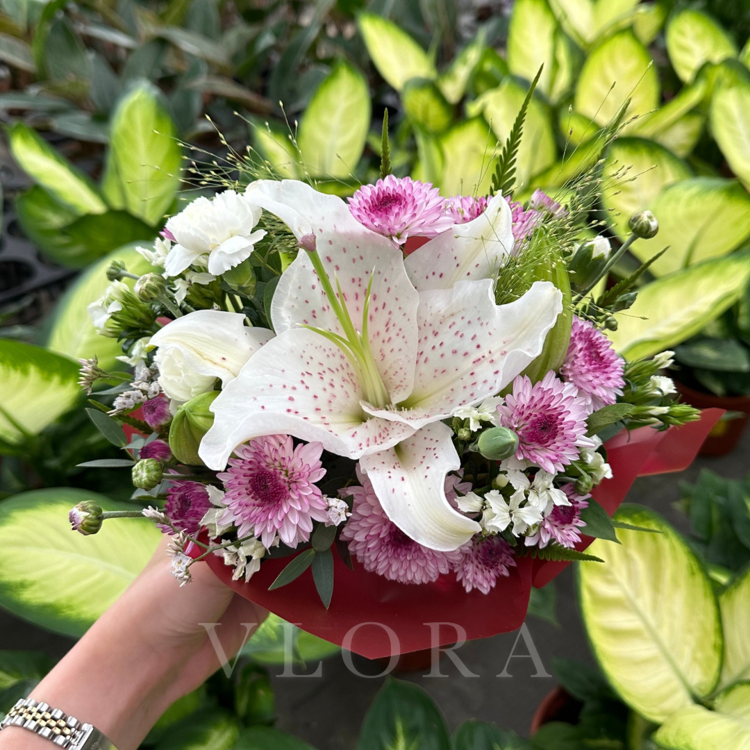 Bouquet of white and pink flowers held by a hand with a blurred background