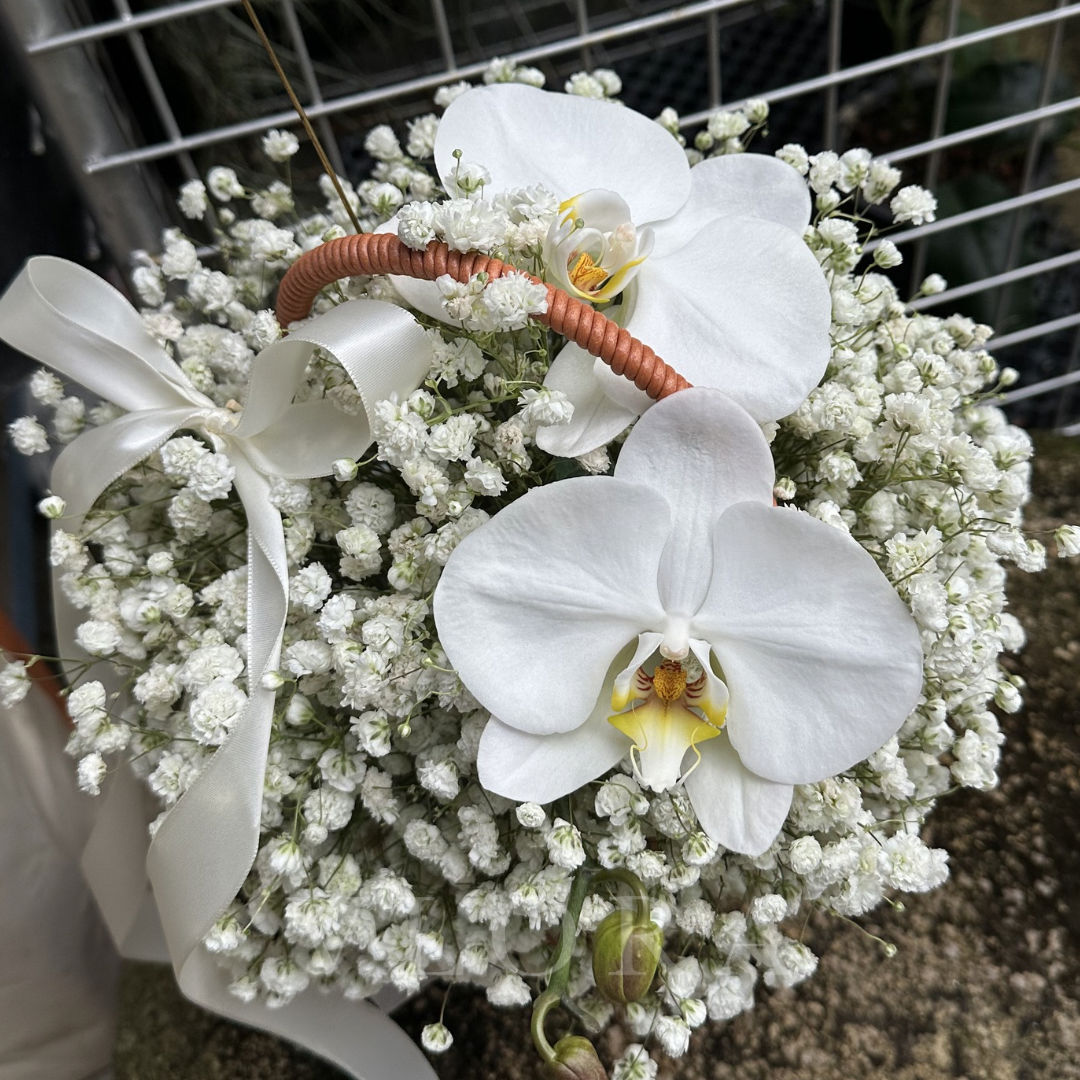 White orchids with a small basket on a bed of baby's breath