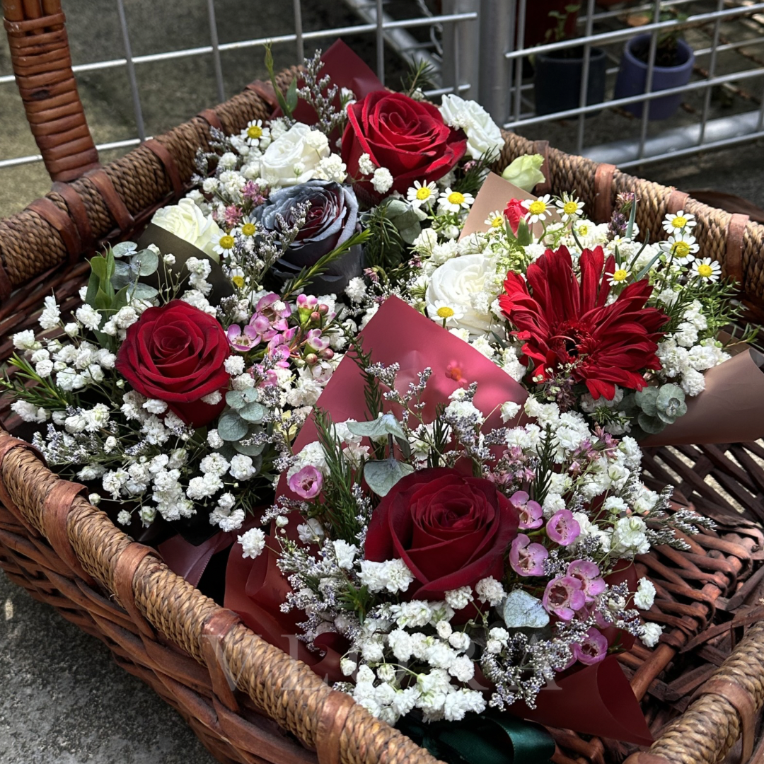 Basket filled with various flower bouquets including red roses and white flowers.