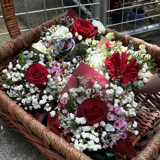 Basket filled with various flower bouquets including red roses and white flowers.