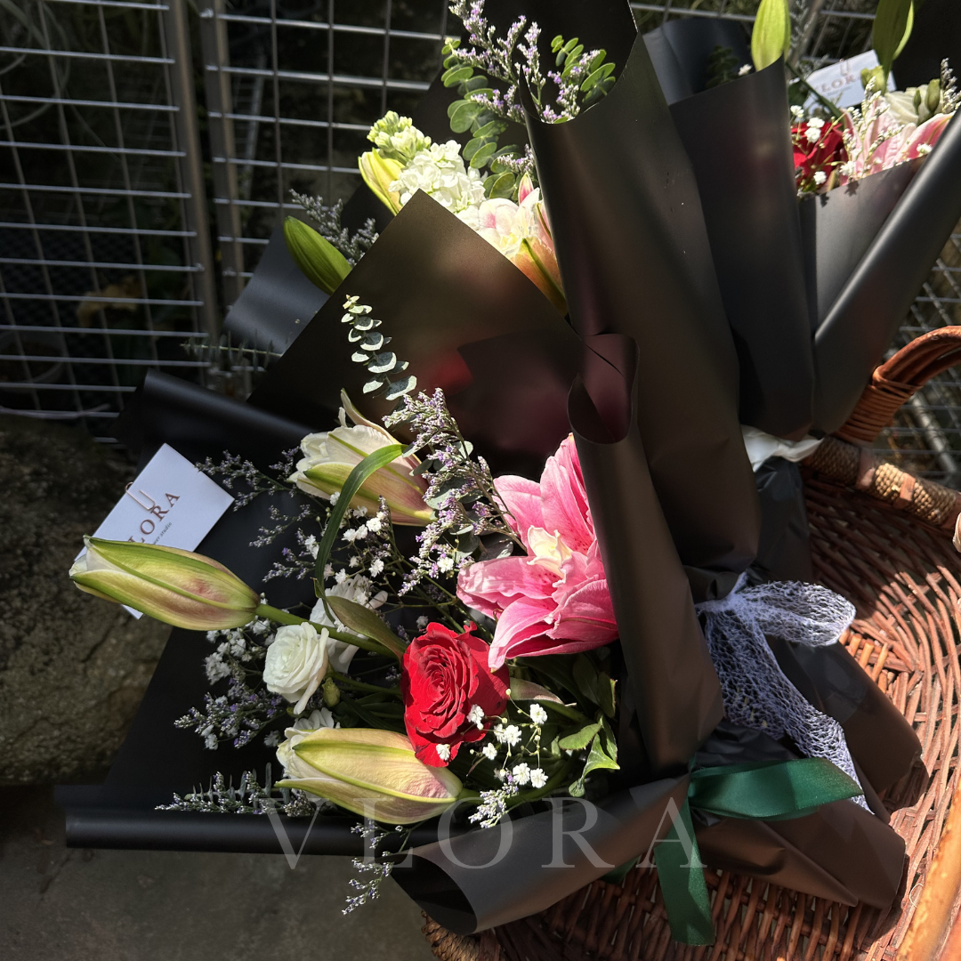 Bouquet of double petal lily flowers wrapped in black paper on a textured surface